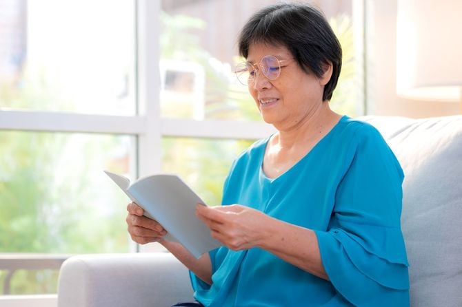 女性が家の居間でリラックスしてソファに座って本を読む