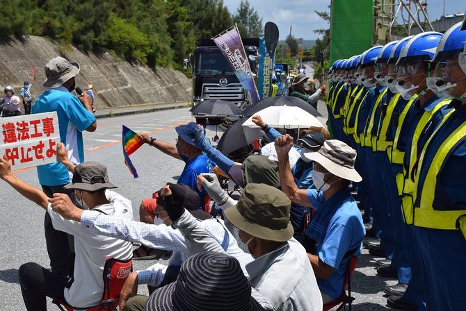 米軍普天間飛行場（宜野湾市）の名護市辺野古移設で、埋め立て用の土砂が搬入される米軍キャンプ・シュワブのゲート前に座り込んで抗議する人たち＝2022年8月25日、沖縄県名護市