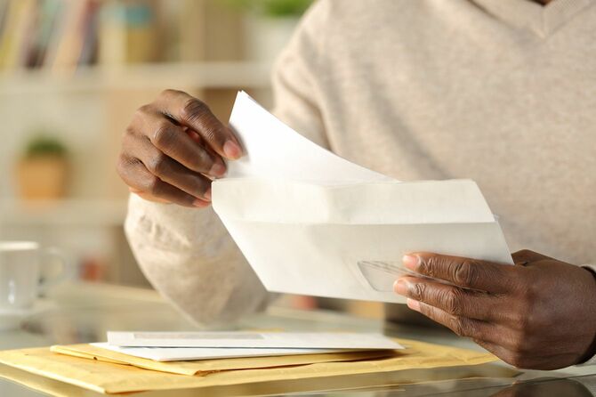 アフリカ系アメリカ人の男性が封筒に書類を入れている