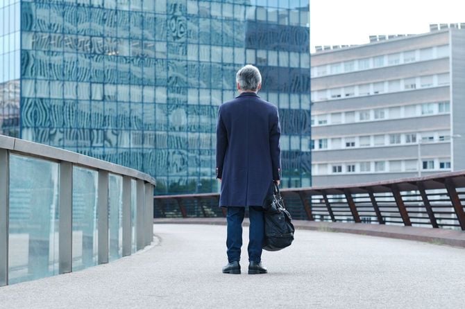 人けのない時間帯のオフィス街に立ち尽くす男性の後ろ姿