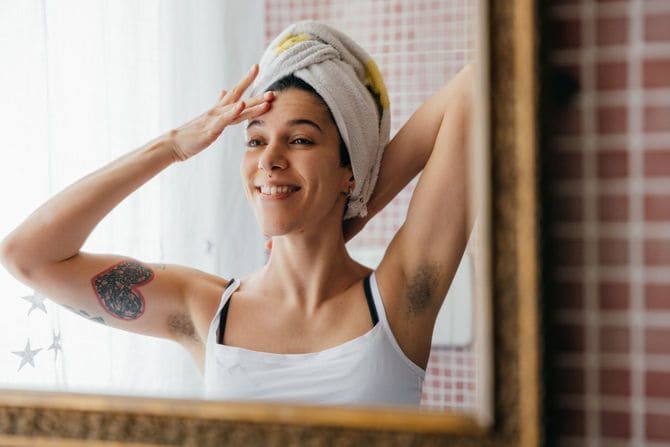 バスルームで朝のスキンケアをするワキ毛の生えた女性