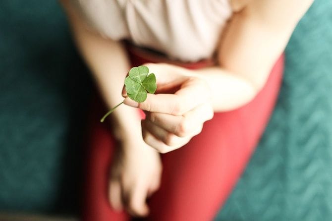 女性は四つ葉のクローバーを持っています
