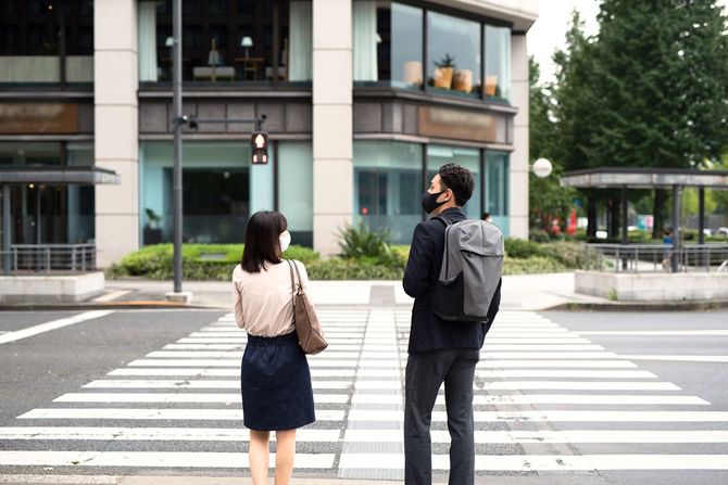 横断歩道で信号が青に変わるのを待っている男女