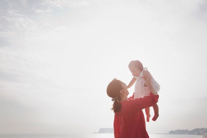 母と赤ちゃんの女の子が海辺でリラックス