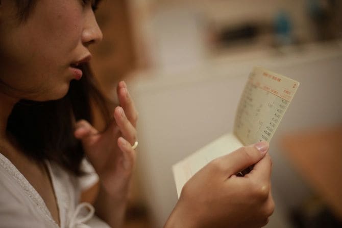 通帳を見て心配している女性