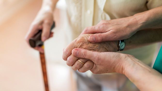 高齢者の手を握る看護師の手元