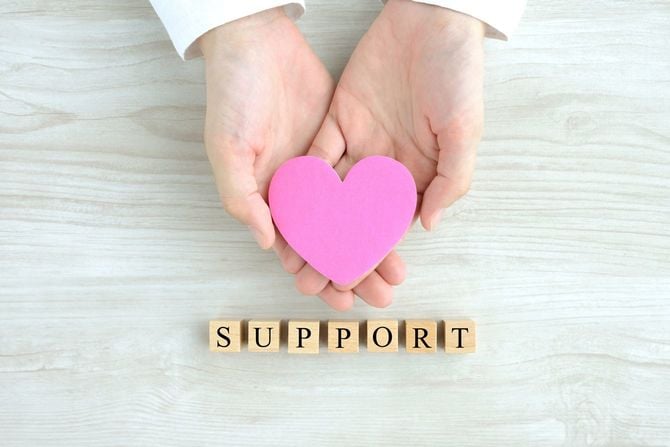 ハートを持つ手と「サポート」という木のブロック
