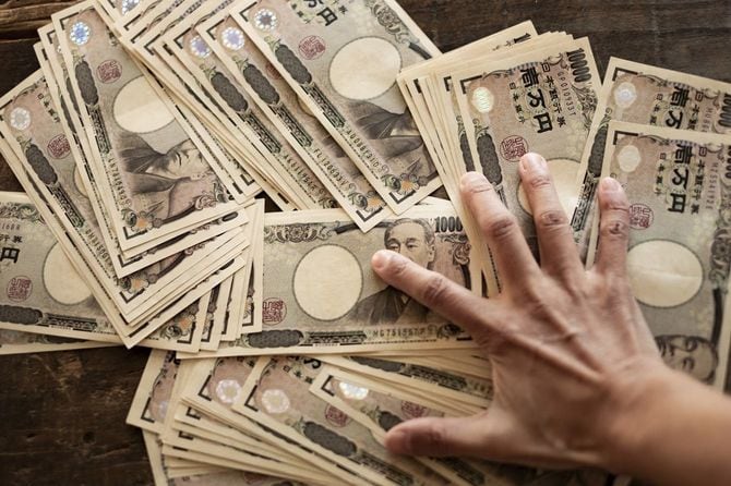 たくさんの一万円札をわしづかみしようとしている手元