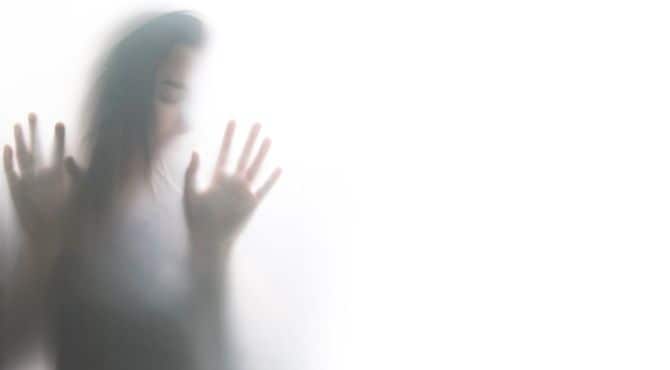 すりガラスの向こう側で、ガラスに身を寄せている女性