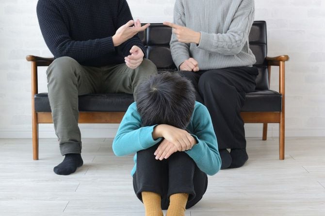 喧嘩する両親の前で膝を抱えて小さくなる子供