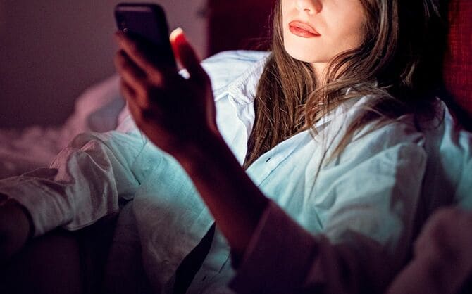 夜のベッドでテキストメッセージを送信する女性