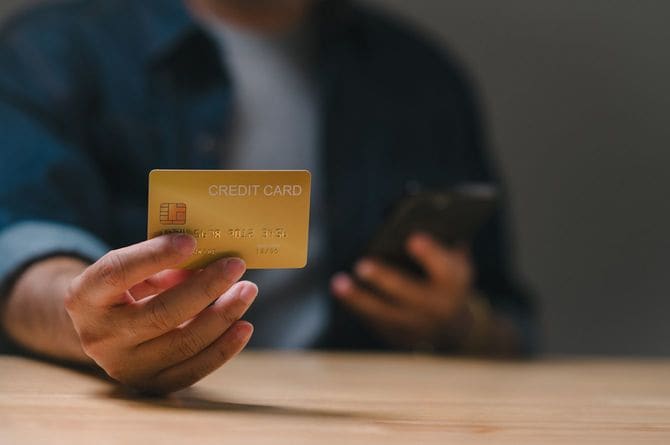 クレジットカードを見ながらスマートフォンを操作している男性