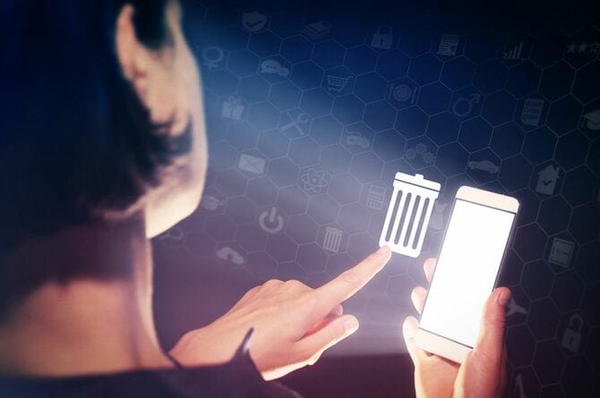 スマートフォンを操作してゴミ箱のアイコンをタップする人