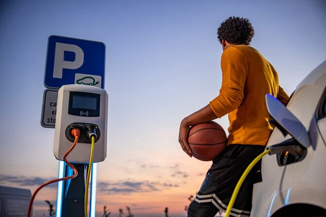 電気自動車が充電完了するのを待っているバスケットボール選手