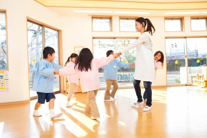 輪になって踊る子供と幼稚園教諭