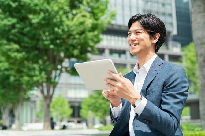公園でタブレット端末をチェックする若い実業家
