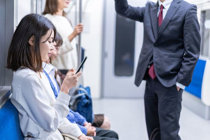 電車の中でスマホを見ている人