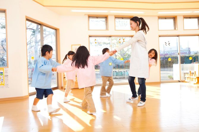輪になって踊る子供と幼稚園教諭