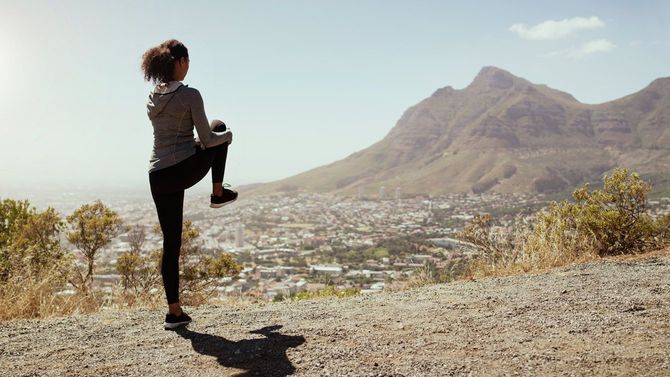 野外トレーニング前にストレッチする若いスポーティーな女性
