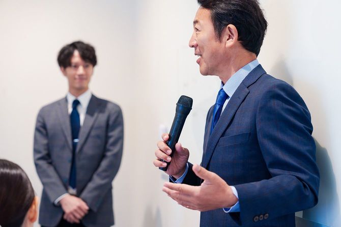 マイクでスピーチをする中年男性