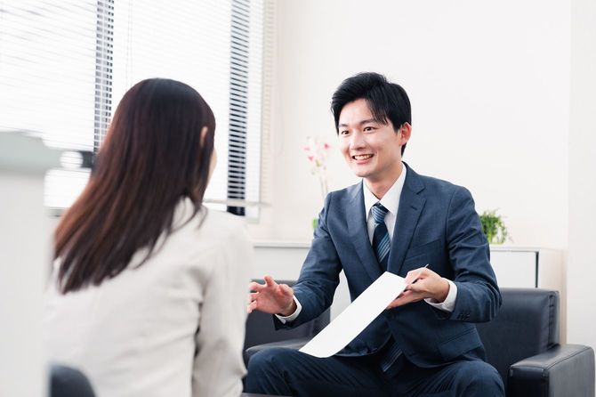 笑顔で書類を提示するセールスマン