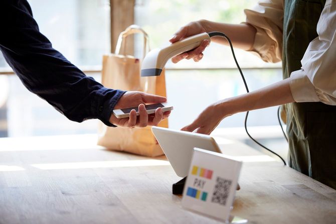 スマートフォンに表示したコードで支払いをする客