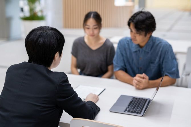 スーツを着た担当者に説明を受ける夫婦