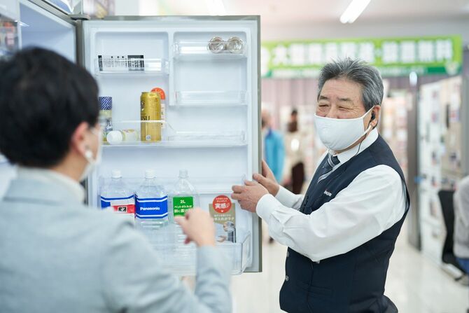 冷蔵庫売り場で接客するノジマのシニア従業員