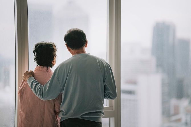 高層ビルの窓の外を見るシニアカップル