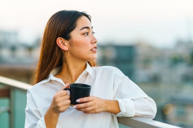 バルコニーでマグカップを持っている女性