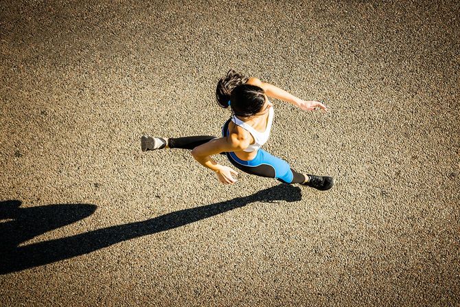路上で走っている若いスポーティな見た目の女性。