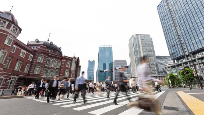 出勤の時間帯に東京駅前の交差点を渡る人々