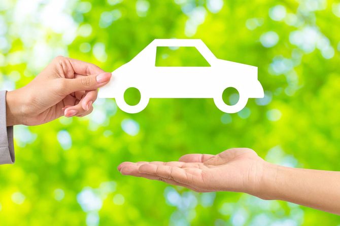 車の形をした白い紙を渡す女性の手