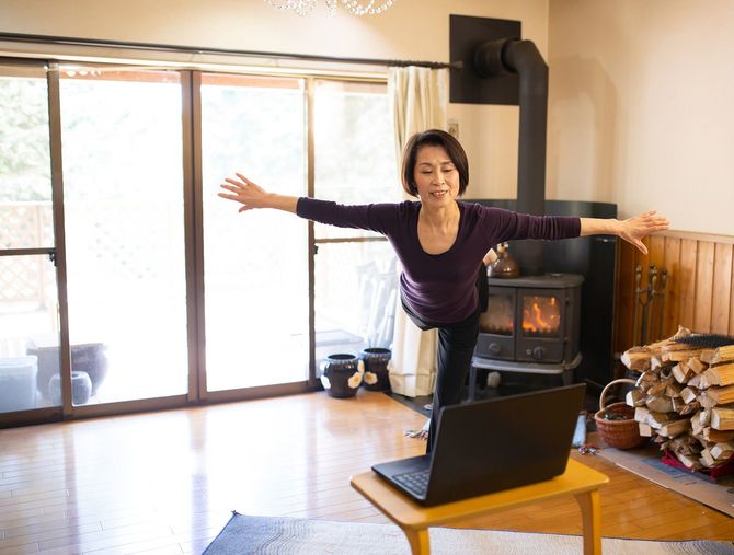 PCを見ながら体操をするシニア女性