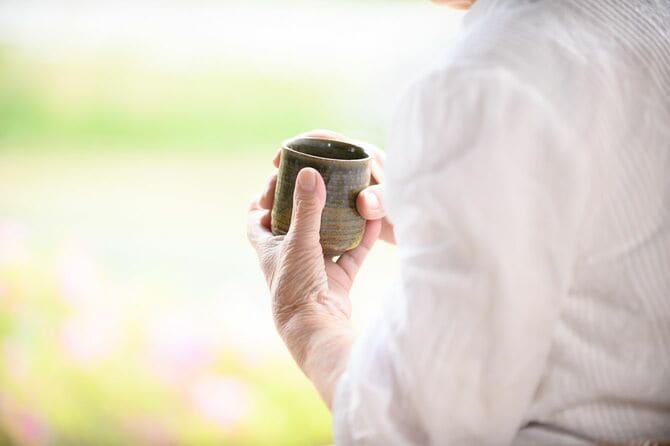 椅子に座ってお茶を飲む年配の日本人女性