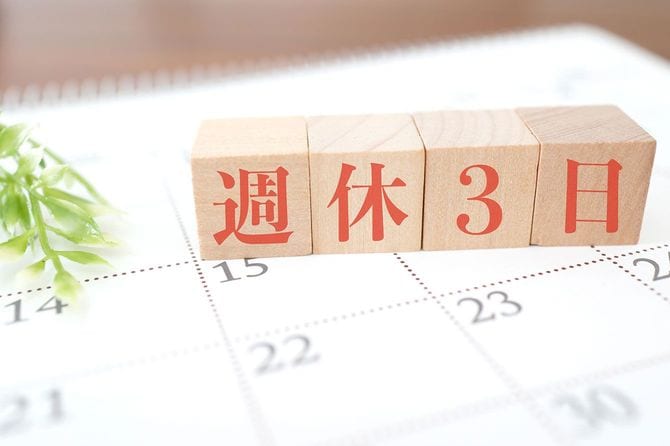 カレンダーの上に並んだ「週休3日」の木製ブロック
