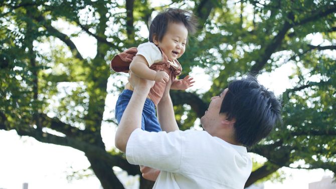 父親がたかいたかいをして笑顔がはじける赤ちゃん