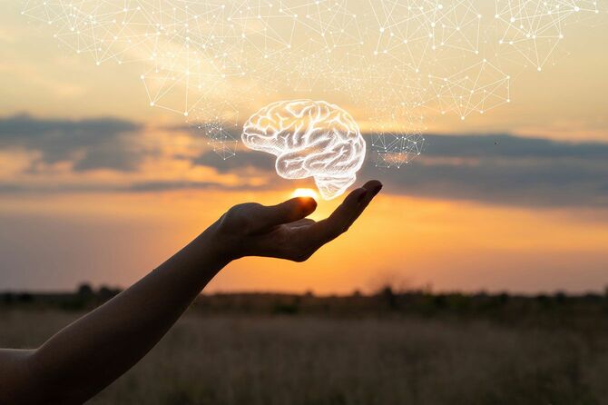 太陽を背景に、手のひらに透明な脳を乗せているイメージ