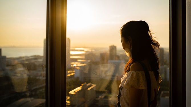 窓から夕日を見ている女性