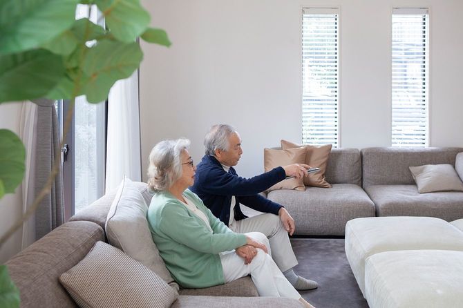 自宅でテレビを見ているアジアのシニアカップル。