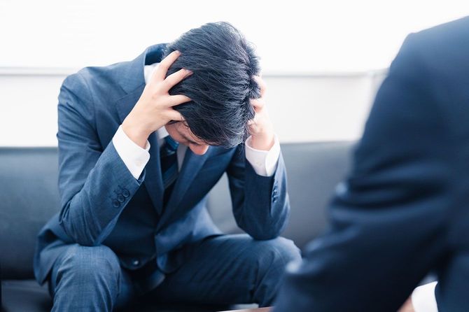 上司に叱られて頭を抱えているビジネスマン