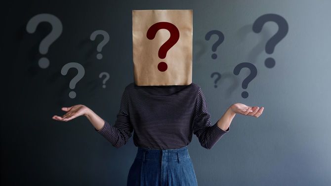 たくさんの疑問符、頭にも疑問符の袋をかぶる若者