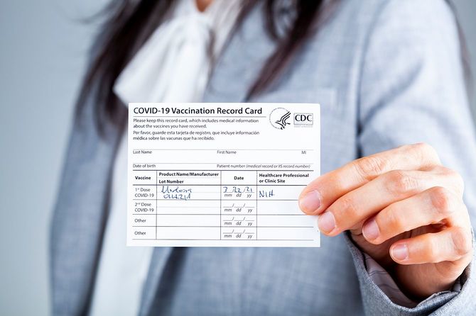 ワクチン接種記録カードを示す女性