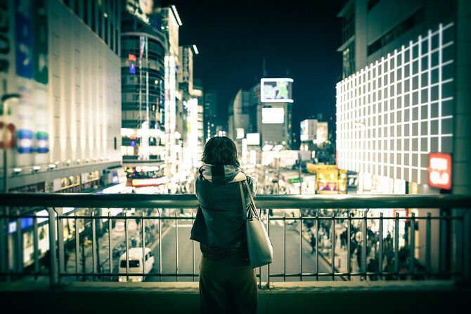 都会の夜景を眺めている若い女