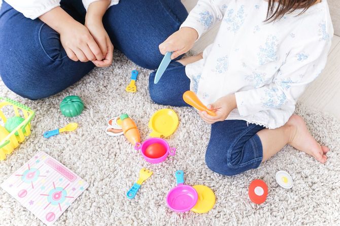 おもちゃを使っておままごとをする子供とそれに寄り添う母親