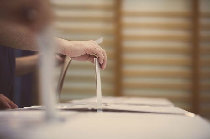 投票箱に投票用紙を入れる手