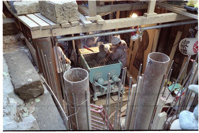 ミキサーにセメントを投入する岡さん。2007年ごろ撮影。