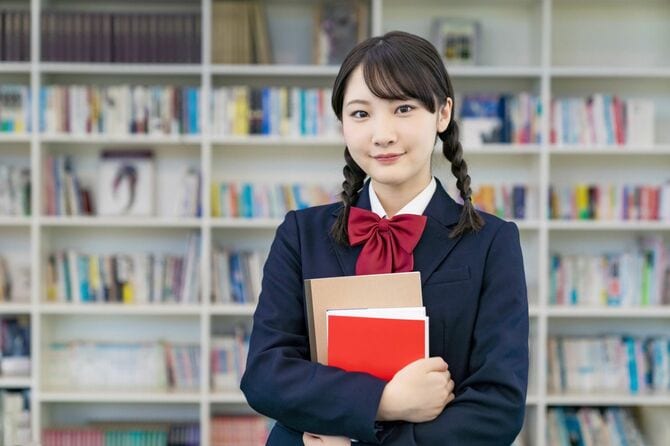 図書館で本を持つ女子高校生