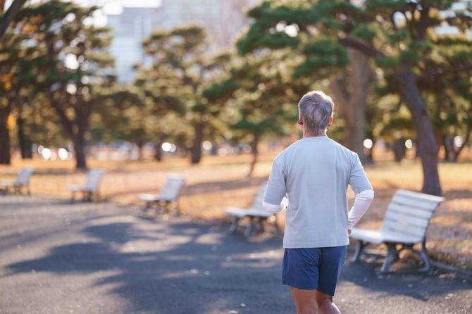 公園の小道でジョギングしている男性の後ろ姿