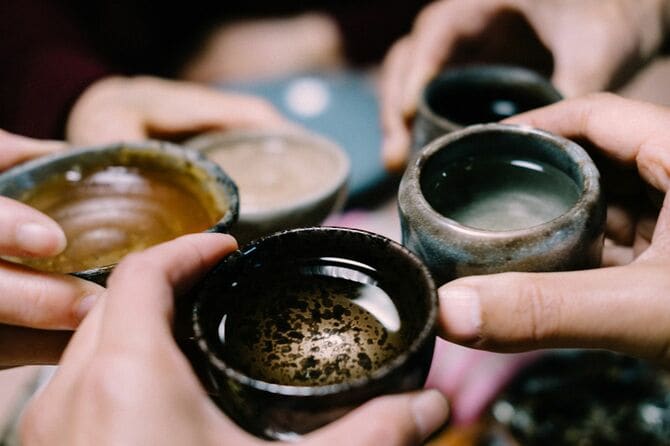 お猪口に注がれた日本酒で乾杯する人々